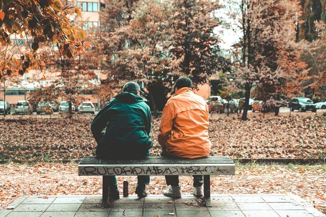 Two men beside one another on a bench.