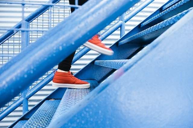 A person's feet pictured walking up a set of stairs.